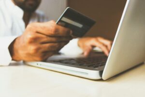 Person handlar online med ett betalkort framför en bärbar dator