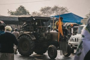 Män på och kring en traktor vid en tillställning med flera fordon och tält.